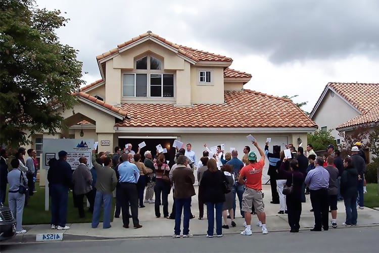house foreclosed on goes to auction. People standing outside of the home bidding. 