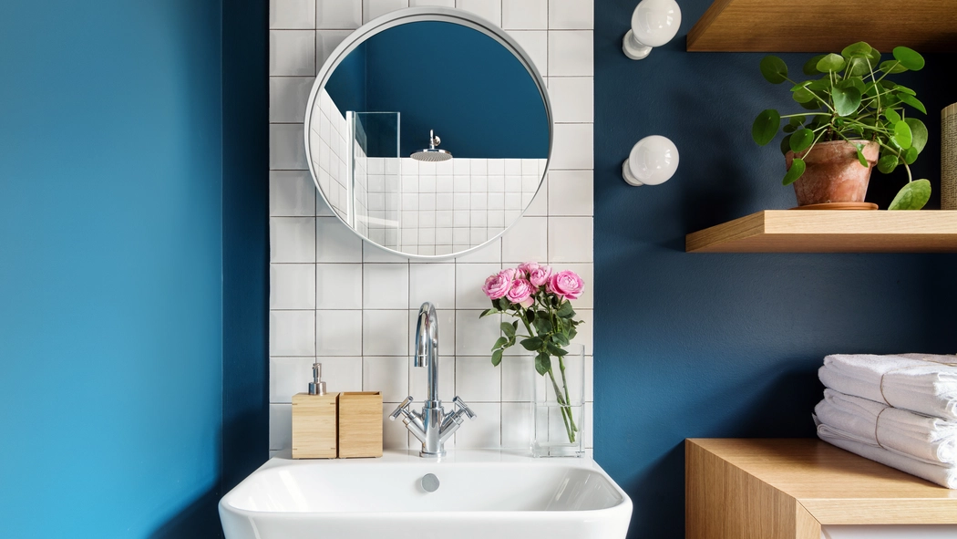 Airbnb bathroom with a blue wall, shelves and a circle mirror