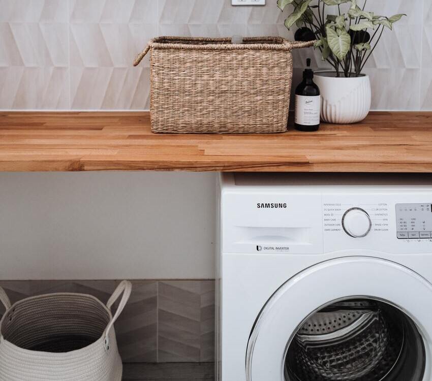 Airbnb essentials, organized laundry room with a folding table on top of the washer 